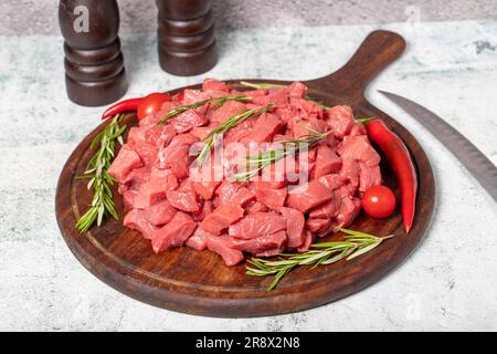 Raw beef meat chopped in cubes. Diced beef or lamb on a wooden serving board Stock Photo