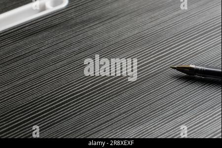 A pen on a wooden textured table with partial shadows, after some edits. Stock Photo