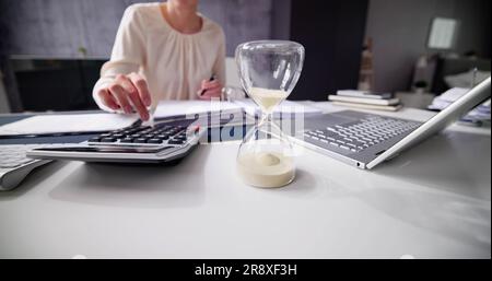 Late Invoice And Billing Deadline With Hourglass At Desk Stock Photo