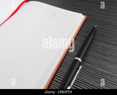 A pen and book placed on textured table, after some edits. Stock Photo