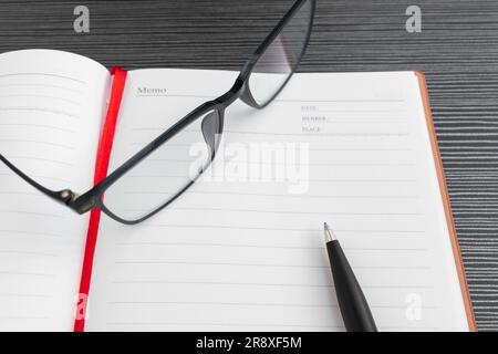 A pen, book and sunglasses placed on a textured table, after some edits. Stock Photo