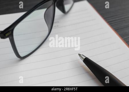 A pen, book and sunglasses placed on a textured table, after some edits. Stock Photo