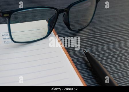 A pen, book and sunglasses placed on a textured table, after some edits. Stock Photo