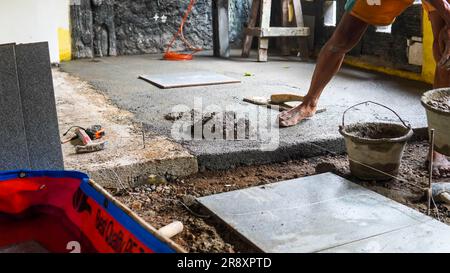 A male construction worker installs a large ceramic tile Stock Photo