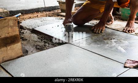 A male construction worker installs a large ceramic tile Stock Photo