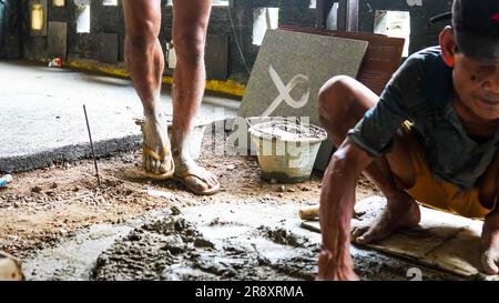 A male construction worker installs a large ceramic tile Stock Photo