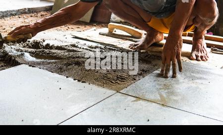A male construction worker installs a large ceramic tile Stock Photo