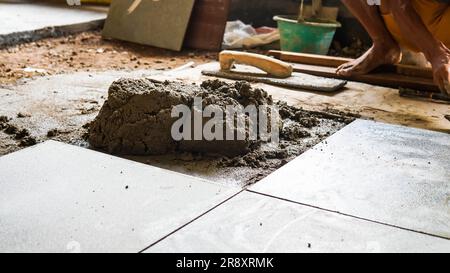 A male construction worker installs a large ceramic tile Stock Photo