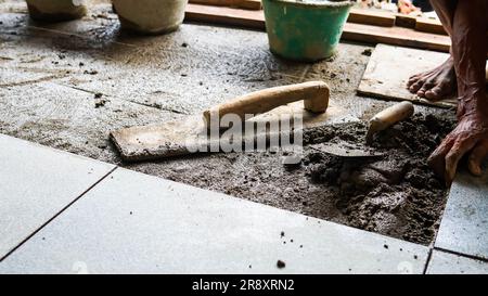 A male construction worker installs a large ceramic tile Stock Photo