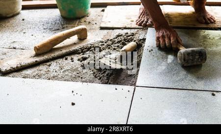 A male construction worker installs a large ceramic tile Stock Photo