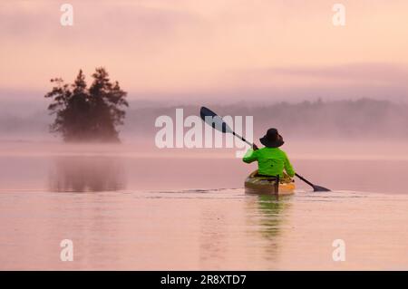 A woman kayaking in Birch Lake, Boundary Waters Wilderness Canoe Area, Minnesota, USA. Stock Photo