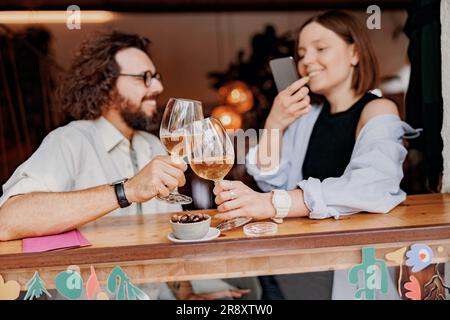 Couple during date drinking wine and making photo while sitting in bar Stock Photo
