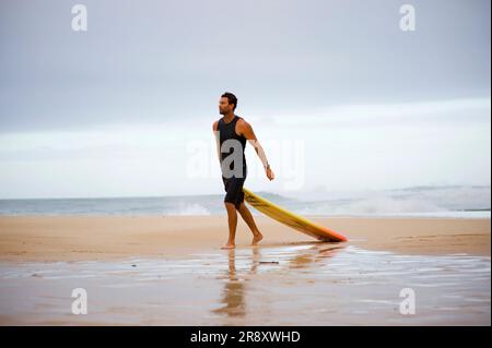 A surfer comes walks along the shore with a newly broken board after taking on the masisve waves a day before the 25th Eddie Aikau Big Wave Invitational. The biggest swell on the N Stock Photo