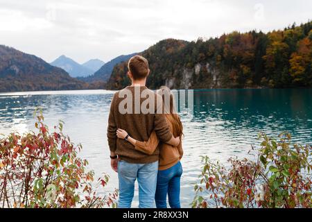 young couple of tourists embrace near an alpine lake Stock Photo