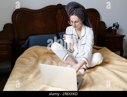 young woman with laptop in bed starts her day Stock Photo