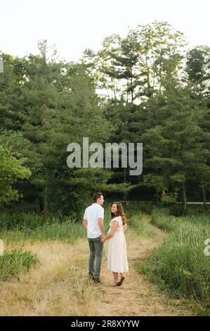 Happy husband and pregnant wife walking away into forest Stock Photo