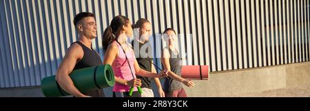 Happy men and women holding sports mats and skipping rope Stock Photo