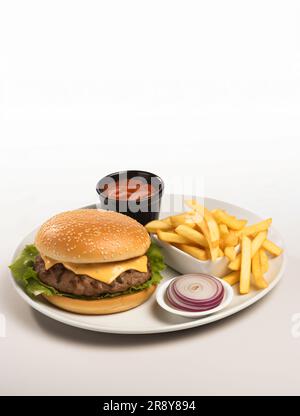 A Beefburger, fries, onion and ketchup on a plate on a white background with copy space above the subject Stock Photo