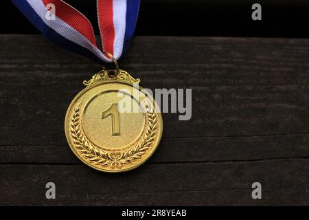 Blurred of woman hands raised and holding gold medals with Thai ribbon against blue sky background to show success in sport or business, Winners succe Stock Photo