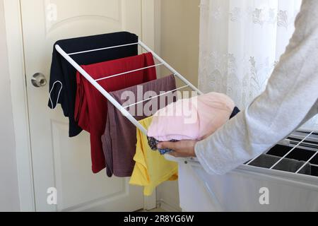 Clean laundry hanging on drying rack in room. Many or lots of washed laundry lined up to be dry. Stock Photo