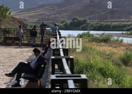 June 21, 2023, Jolfa, East Azerbaijan, Iran: People stand near the Aras River at the border between northwestern Iran and Azerbaijan. The Aras (the Araks, Arax, Araxes, or Araz) is a river in the Caucasus. It rises in eastern Turkey and flows along the borders between Turkey and Armenia, between Turkey and the Nakhchivan exclave of Azerbaijan, between Iran and both Azerbaijan and Armenia, and, finally, through Azerbaijan where it flows into the Kura River. It drains the south side of the Lesser Caucasus Mountains while the Kura drains the north side of the Lesser Caucasus. The river's total le Stock Photo