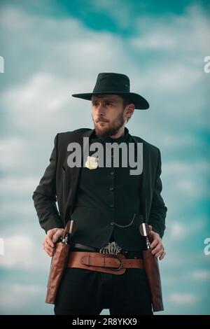 Sheriff officer in black suit and cowboy hat. Man with wild west guns, vintage pistol revolver and marshal ammunition. US Marshals, American western S Stock Photo