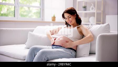 Close-up Of Pregnant Woman Applying Cream On Her Belly Stock Photo