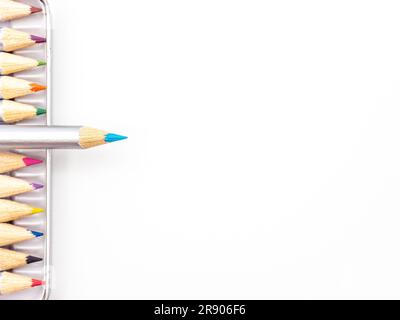 A vibrant array of colored pencils in a metal tin container against a white background Stock Photo