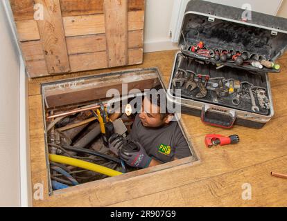 Netherlands, The Hague; plumber is repairing part of copper piping under the floor. Stock Photo