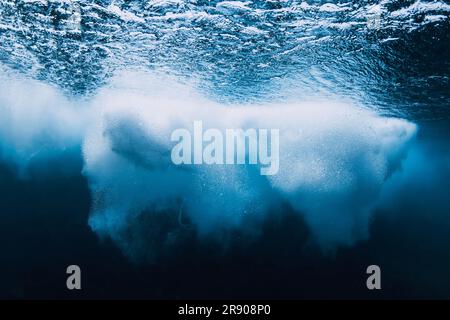 Ocean wave with foam underwater in blue water. Stock Photo