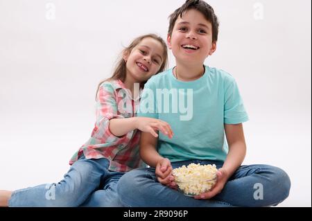 Preteen boy and little girl, brother and sister watching cartoons eating popcorn. kids. Lifestyle. Entertainment Stock Photo