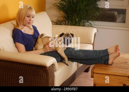 Woman with pug on sofa, Jennifer Toebben, curly Stock Photo