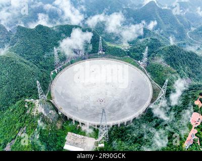 Pingtang. 22nd June, 2023. This aerial photo taken on June 22, 2023 shows China's Five-hundred-meter Aperture Spherical Radio Telescope (FAST) under maintenance in southwest China's Guizhou Province. China's FAST telescope identified a binary pulsar with an orbital period of 53.3 minutes, the shortest known period for a pulsar binary system. The research, mainly conducted by a team led by scientists from the National Astronomical Observatories of the Chinese Academy of Sciences (NAOC), was published in the journal Nature Wednesday. Credit: Ou Dongqu/Xinhua/Alamy Live News Stock Photo