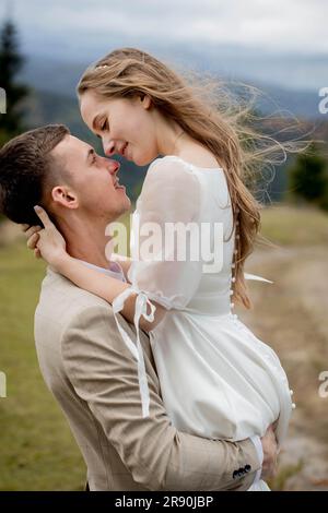 Stylish groom kissing gorgeous bride in sun light, perfect moment, boho wedding couple. Portrait of happy newlyweds on the wedding day. Wedding couple Stock Photo