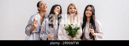 bridal party, multicultural women holding glasses with champagne, bride with white flowers showing her engagement ring, bridesmaids, diversity, positi Stock Photo