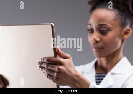 Data and quality control with human oversight. In focus, an electronic device screen displaying results being checked by a blurred researcher. AI-assi Stock Photo