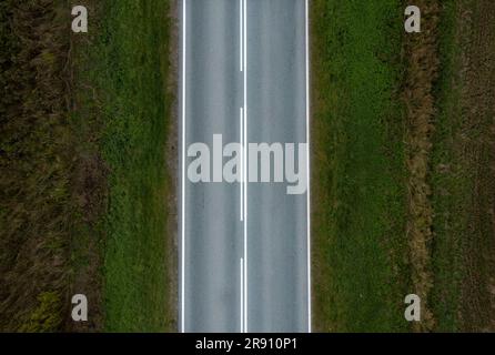 An asphalt road with a continuous lane on one side and a dividing strip on the other. View from above. Stock Photo