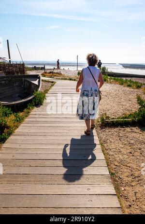 Whitstable North Kent , England UK - Tourist enjoys a late afternoon walk along the seafront boardwalk Stock Photo