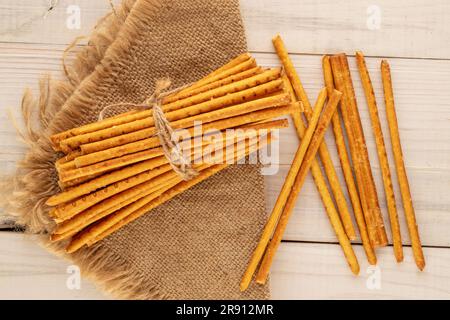 Straw is a bakery product. Several straws with jute napkin on wooden table, macro, top view. Stock Photo