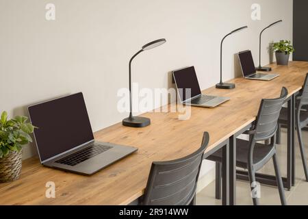 Several laptops standing in a row on a wooden tabletop. Workplaces. Selective focus. Stock Photo