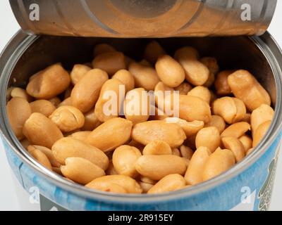 Roasted peanuts in an open jar on orange. Peanuts close up. Stock Photo