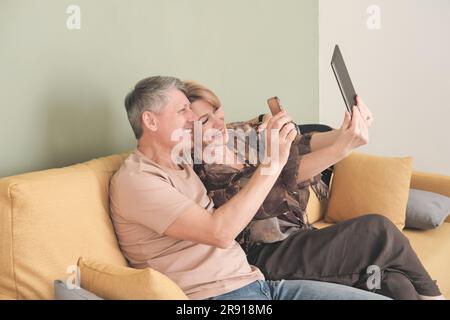 technology and people concept. happy middle age couple with tablet pc computer having video chat at home. Stock Photo