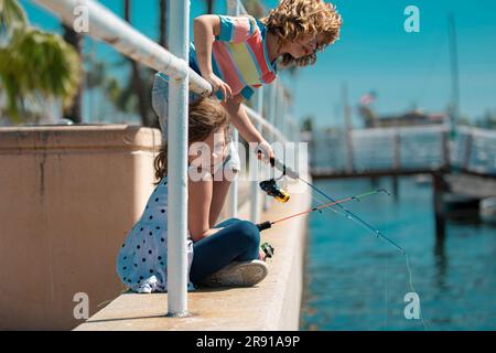 Couple of kids fishing on pier. Child at jetty with rod. Boy and