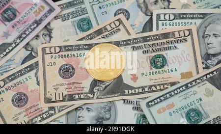 Dogecoin (DOGE) cryptocurrency pictured as a gold coin lying over dollars, real US money, 50 dollars, United States fifty-dollar bill Stock Photo