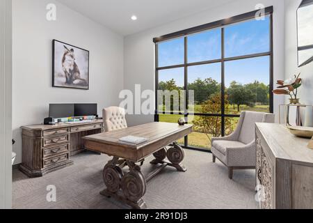The interior of a beautiful home office, complete with a desk set up in front of the large windows Stock Photo