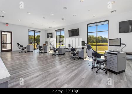 A modern dental office interior featuring multiple comfortable dental chairs and desks for patient care Stock Photo