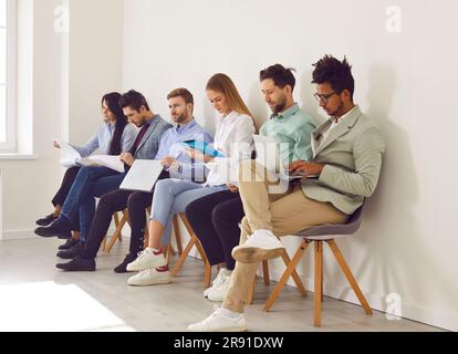 Diverse job applicants sitting in row waiting for job interview in office Stock Photo