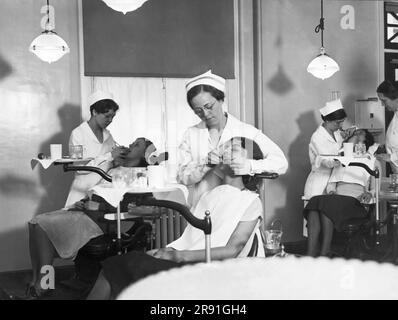 Philadelphia, Pennsylvania:  c. 1926 Students at work on patient's mouths in the oral hygiene clinic of the new Temple University Dental Infirmary. Stock Photo