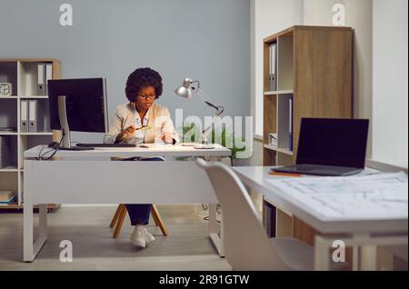 Woman auditor checking financial documents with magnifying glass over office desk. Stock Photo