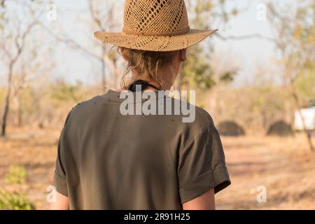 A woman in a sun hat is covered with flies on her back in the heat of the outback in Australia Stock Photo